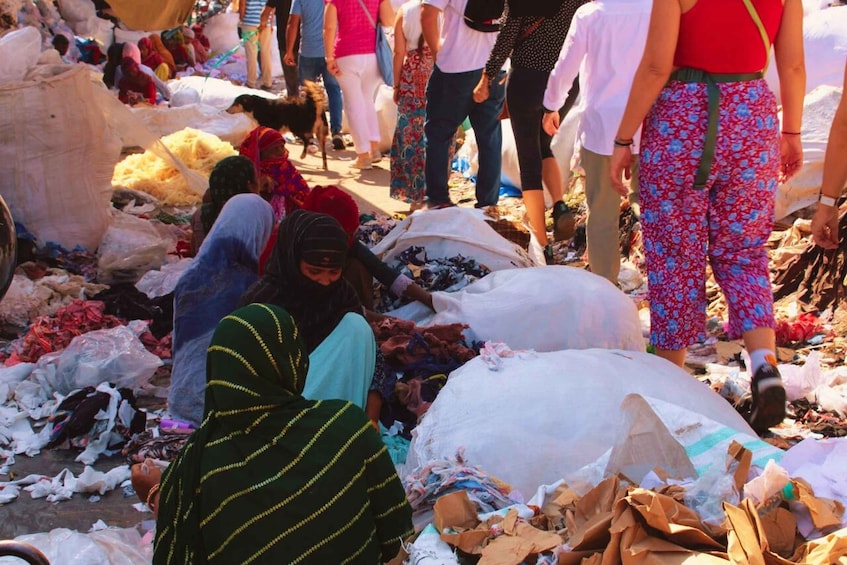 People sorting through piles of discarded textiles in a market setting. 3