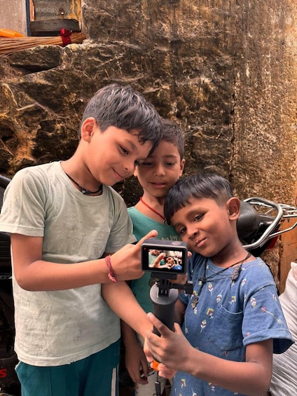 Three children with a smartphone, a motorcycle, and a rocky wall in the background. 2
