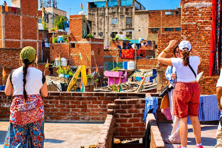 A densely packed urban area with brick buildings, some with visible water tanks. There are clothes hanging on lines, and various household items scattered around. 4