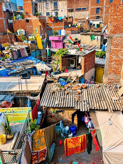 A densely packed urban area with makeshift housing, colorful flags, and various household items scattered around. 3