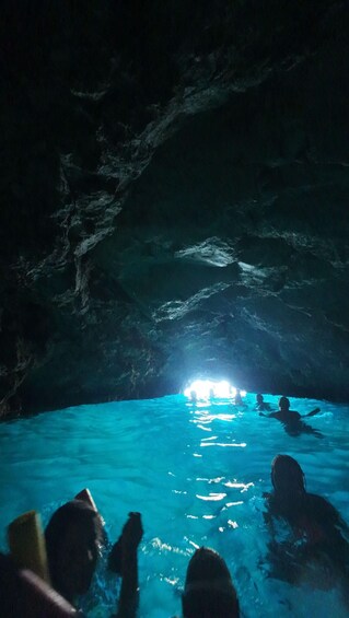 A cave with a pool of water and people swimming. 1