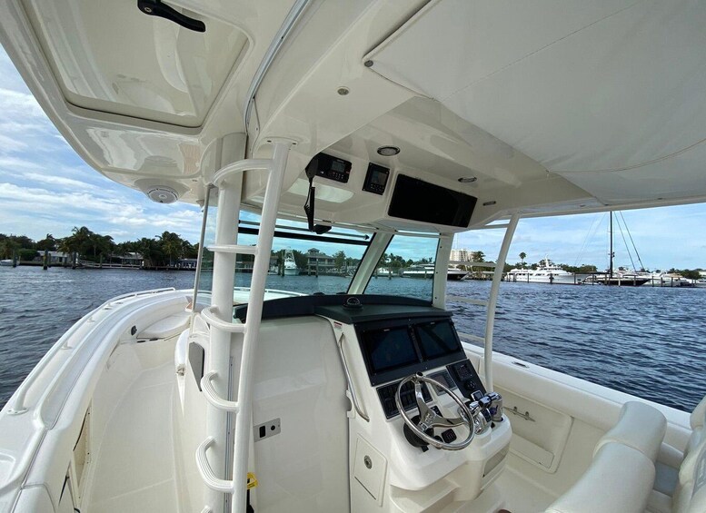 A boat's interior with a steering wheel, control panel, and windows overlooking the water. 1