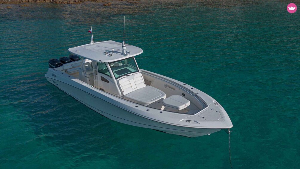 A white motorboat with a cabin and seating area, floating on clear turquoise water. 2