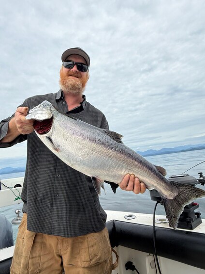 A person holding a large fish on a boat with a cloudy sky in the background. 3