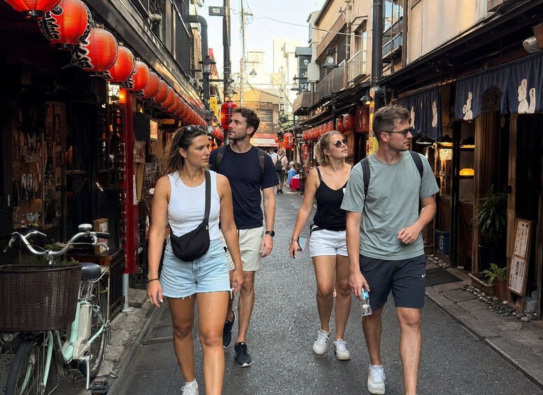 A group of people walking down a narrow street lined with shops and red lanterns. 2