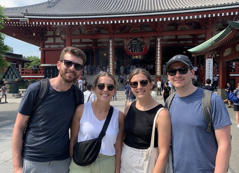 A group of people standing in front of a traditional Japanese building with a curved roof and red pillars. 1