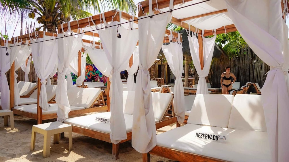 A beachside lounge area with white canopies and sunbeds labeled 'RESERVADO'. 4