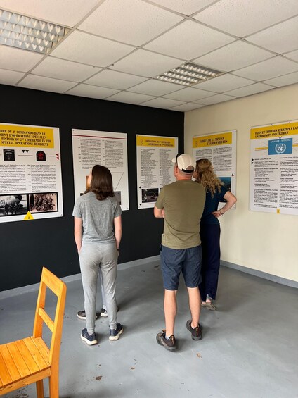 Tre persone osservano dei manifesti informativi su una parete in una stanza. 3