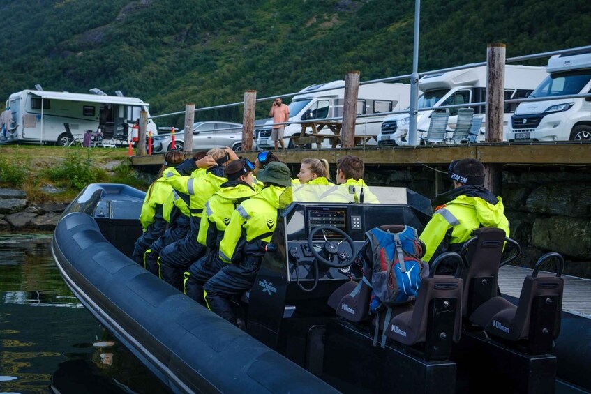 A group of people in bright yellow jackets on a boat docked at a pier with RVs in the background. 5
