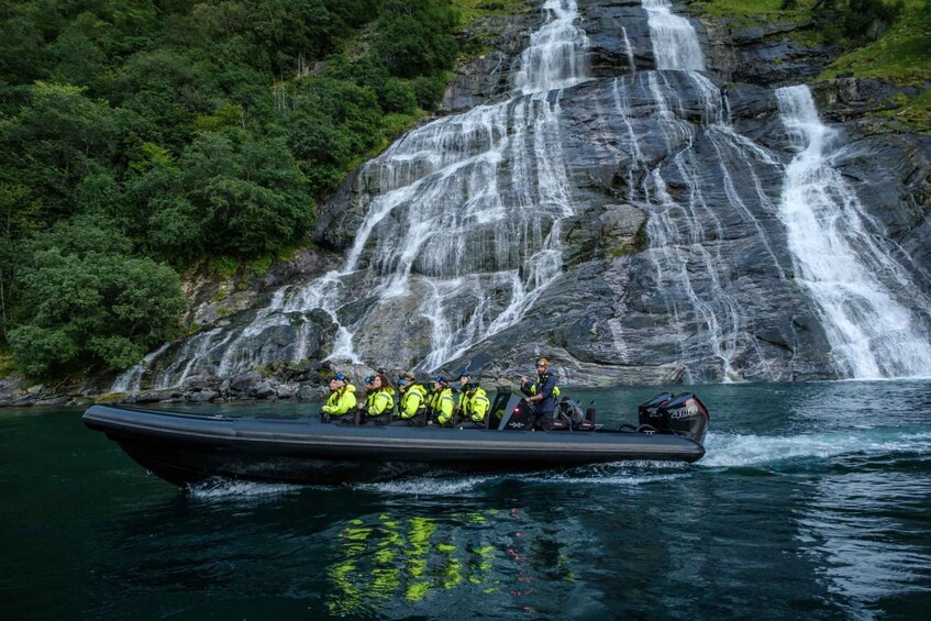 A boat with several people wearing yellow life jackets, navigating near a waterfall. 2