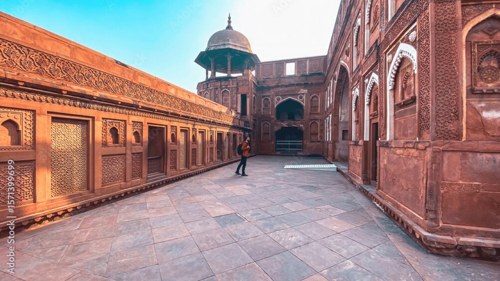 A courtyard with intricate architectural details, a domed structure, and a person walking. 4