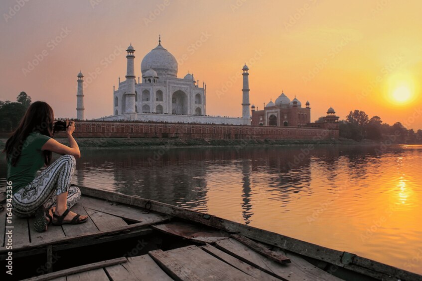 A person taking a photo of the Taj Mahal at sunset. 1