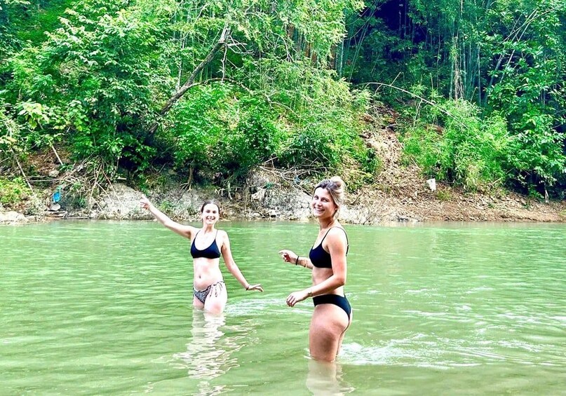Two people in a river surrounded by dense greenery. 3
