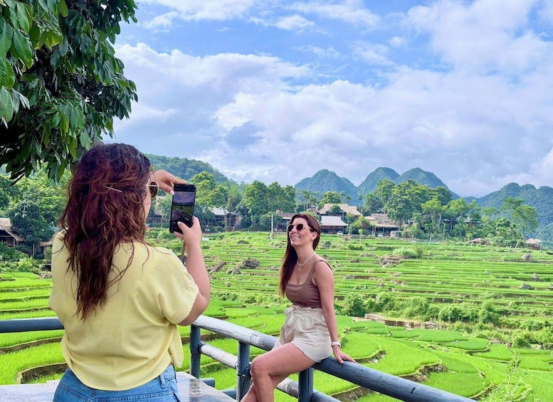 Two people taking a photo of a terraced rice field with mountains in the background. 5
