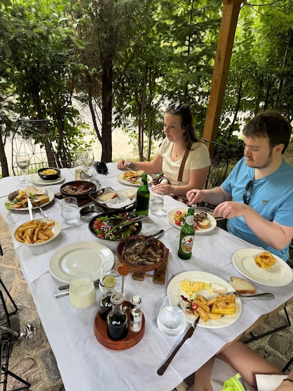 A table set outdoors with various dishes, a bottle of beer, and condiments. 5