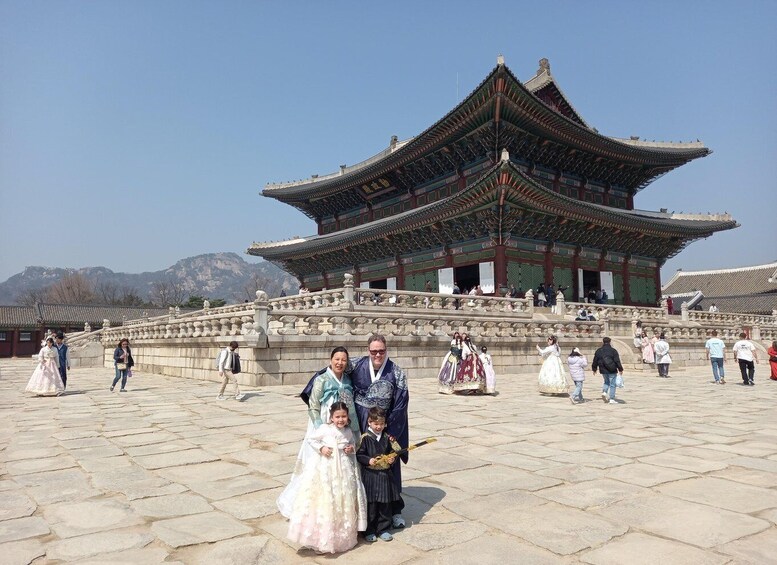 A traditional Korean palace with a large, ornate gate and stone paving in the foreground. 2
