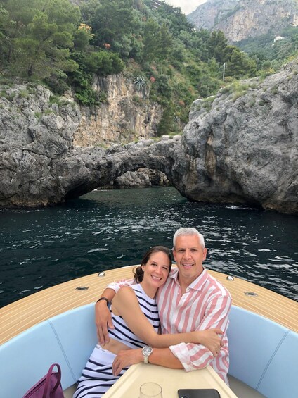 A couple on a boat with a natural rock formation in the background. 2