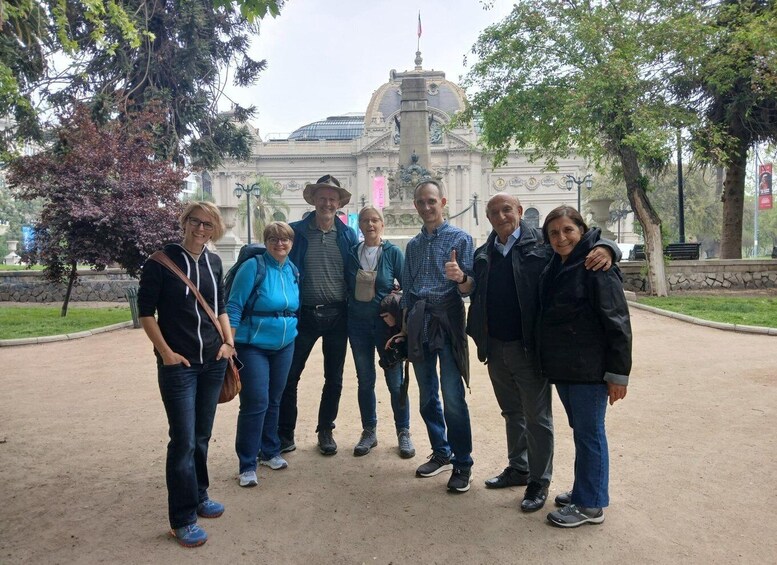 A group of people standing in a park with a large building in the background. 4