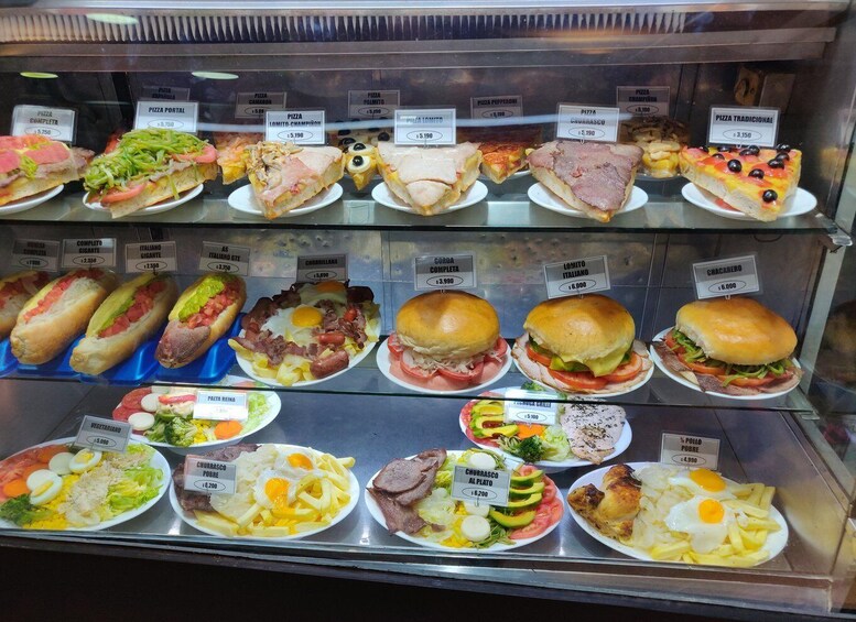 A variety of food items displayed in a glass case, including pizzas, sandwiches, and salads. 2
