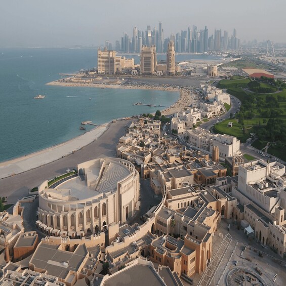 A coastal city with a prominent historical amphitheater, modern skyscrapers, and a beach. 3