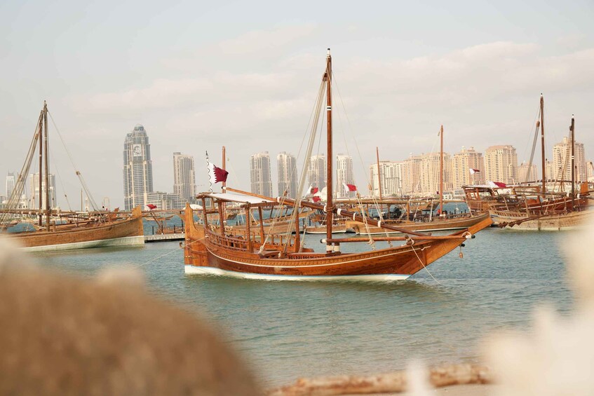 A harbor with traditional wooden boats, a city skyline in the background, and a clear sky. 1