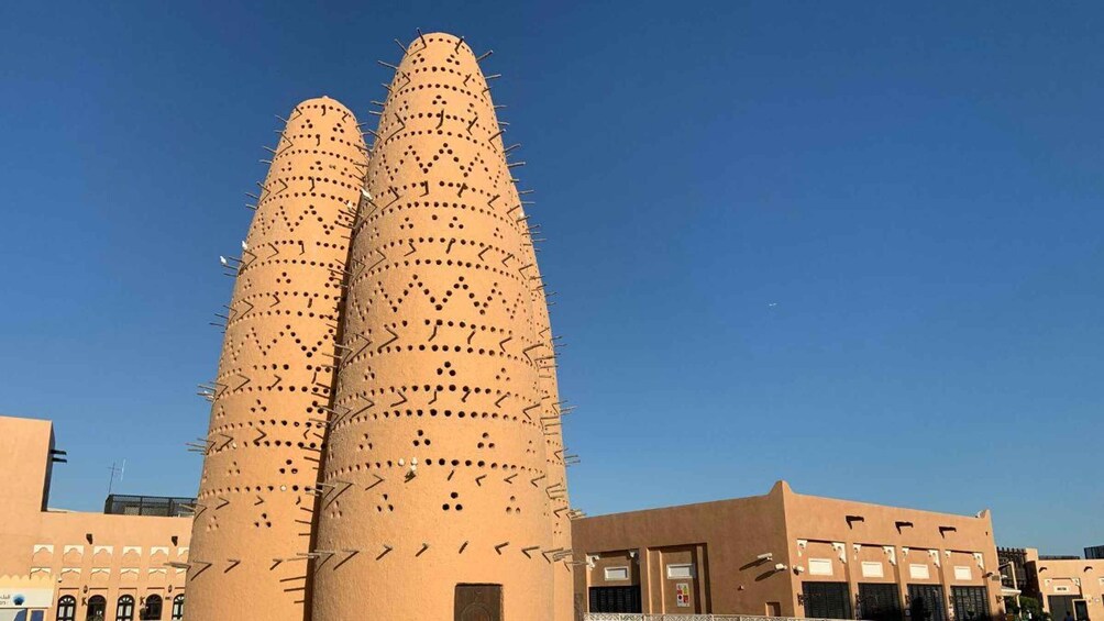 Two tall, cylindrical structures with protruding spikes and dotted patterns, set against a clear blue sky. 4