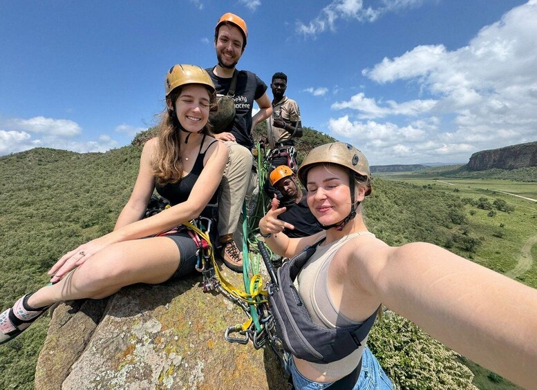 A group of people on a rocky outcrop with a scenic landscape in the background. 5