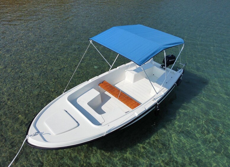 A small white motorboat with a blue canopy, floating on clear water. 5