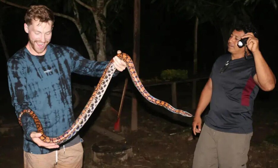 A person holding a large snake with a patterned body. 2