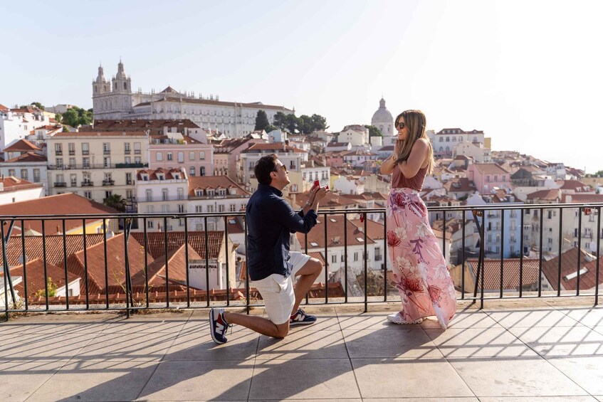 A man kneeling on a balcony, proposing to a woman. 2