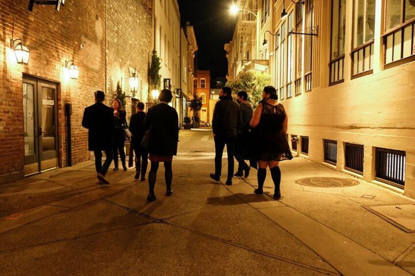 Une scène de rue nocturne, avec des piétons qui se promènent, éclairés par des lampadaires, et des bâtiments dotés de grandes fenêtres et de grandes portes. 1