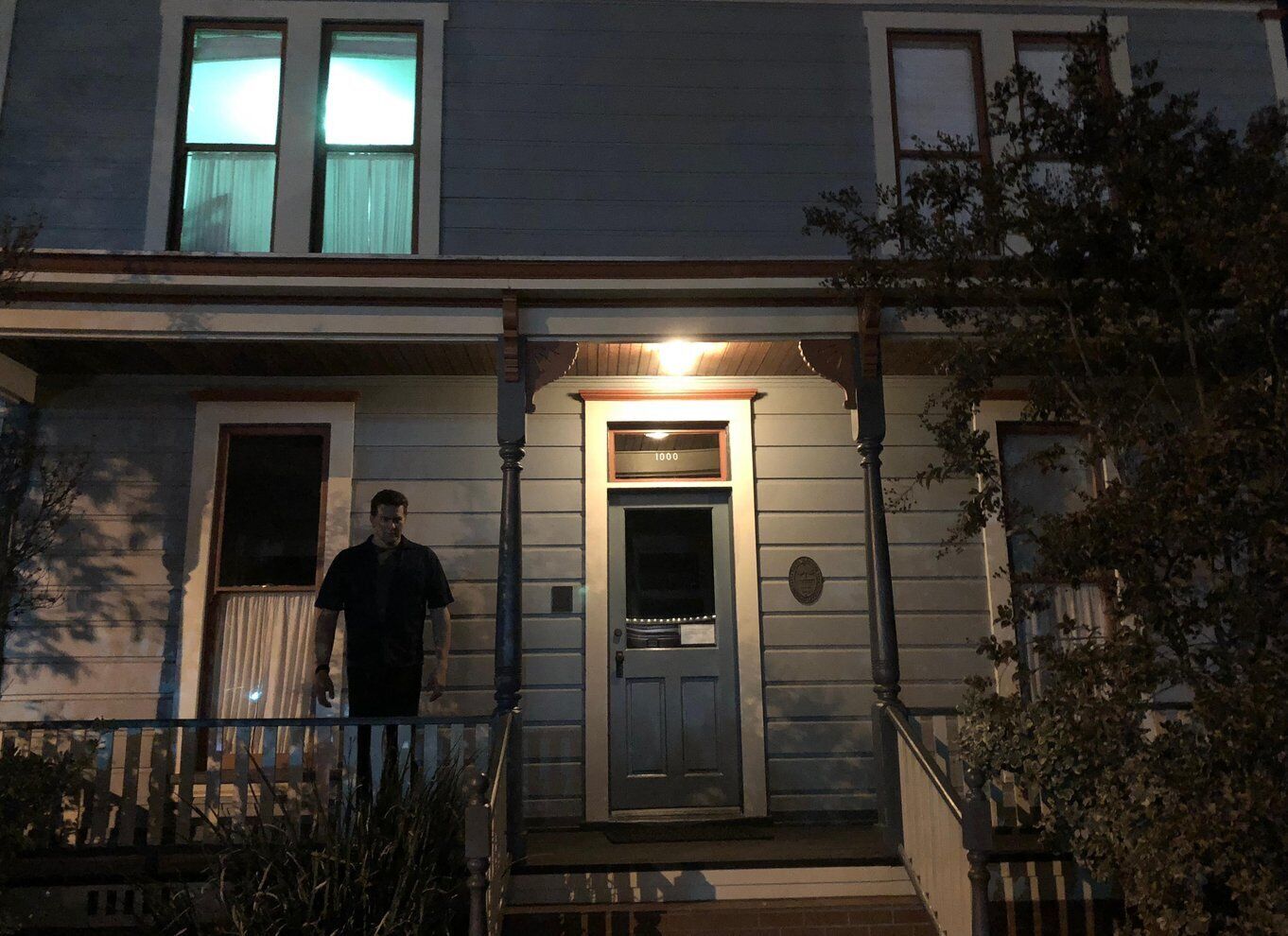 Una casa de dos pisos con una puerta de entrada iluminada, un buzón y una placa de número. 1