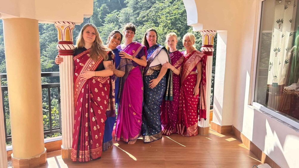 A group of people in traditional attire standing on a balcony with a view of greenery. 4