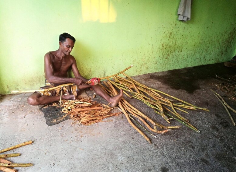 A person sitting on the floor surrounded by cut bamboo sticks. 4
