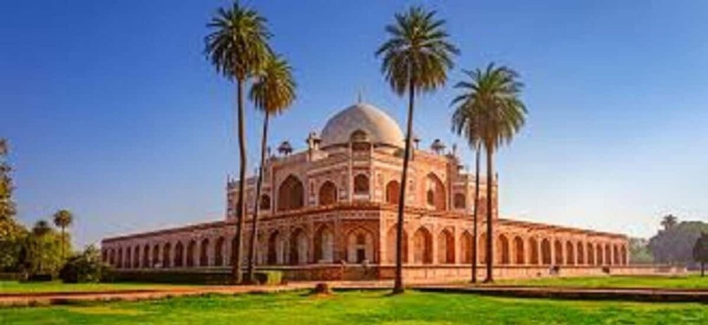 A large, domed building with arched windows and a central dome, surrounded by a green lawn and palm trees. 1