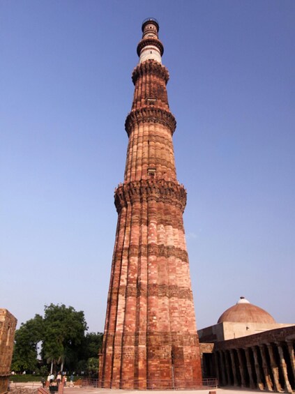 A tall, red brick minaret with a dome at the top, surrounded by trees and other historical structures. 5