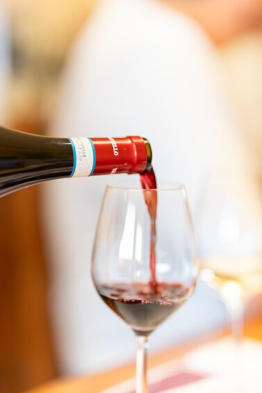 A bottle of red wine being poured into a wine glass. 2