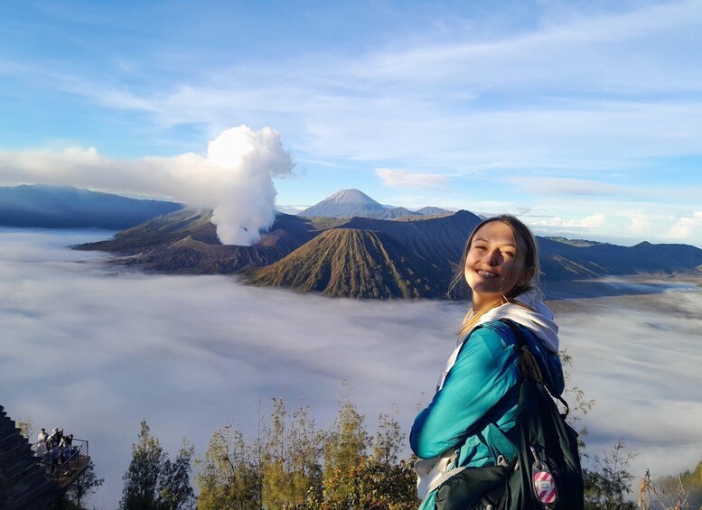 A person standing on a mountain with a volcano in the background. 1