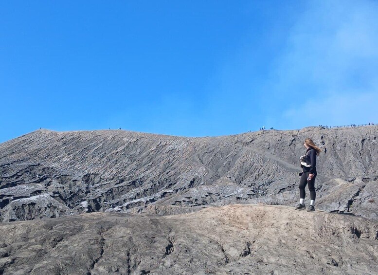 A person hiking on a rocky terrain with a clear blue sky. 3