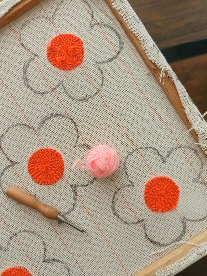 Een detailfoto van een gehaakt project met oranje en roze garen op een beige stof. 3