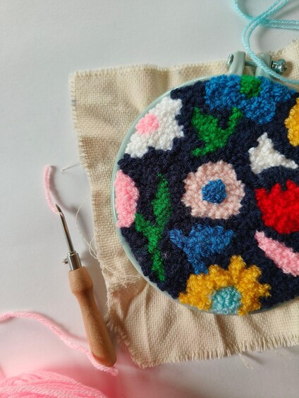 Een kleurrijk gehaakt object met een houten haakpen en roze wol. 1
