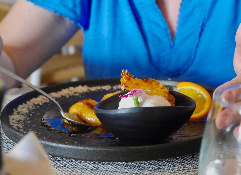 A dessert with a dollop of cream, a flower, and a piece of fried food on a plate. 4