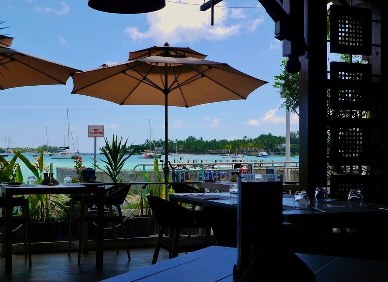 A seaside restaurant with outdoor seating, umbrellas, and a view of the marina. 5