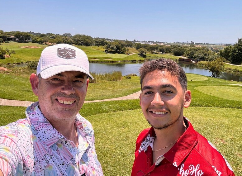 Two people in front of a golf course with a lake and trees in the background. 1