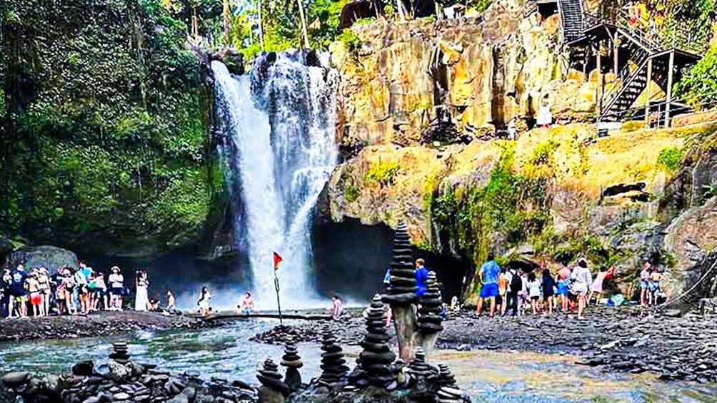 A waterfall surrounded by rocks and a crowd of people. 5