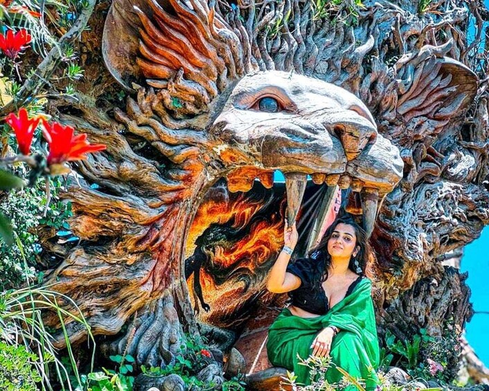 A person sitting in front of a large, intricately carved tree trunk with a lion's face. 4