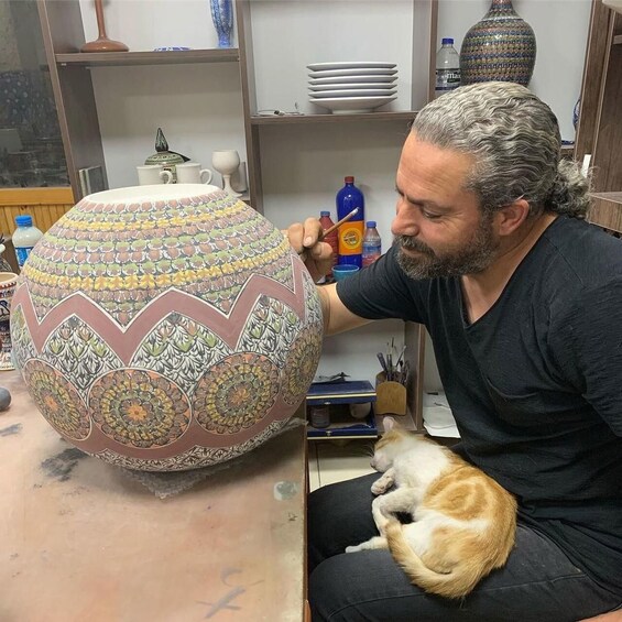 A person painting a large, intricately patterned ceramic pot. 2