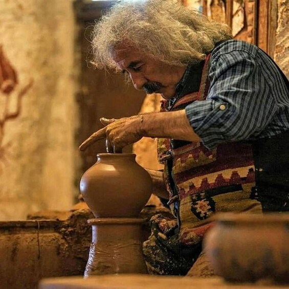 A person shaping a clay pot on a pottery wheel. 5