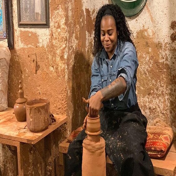 A person working with clay pottery on a wooden table in a rustic workshop. 3