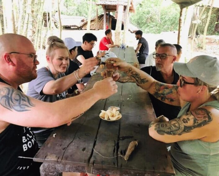 People sitting at a wooden table outdoors, eating food. 4